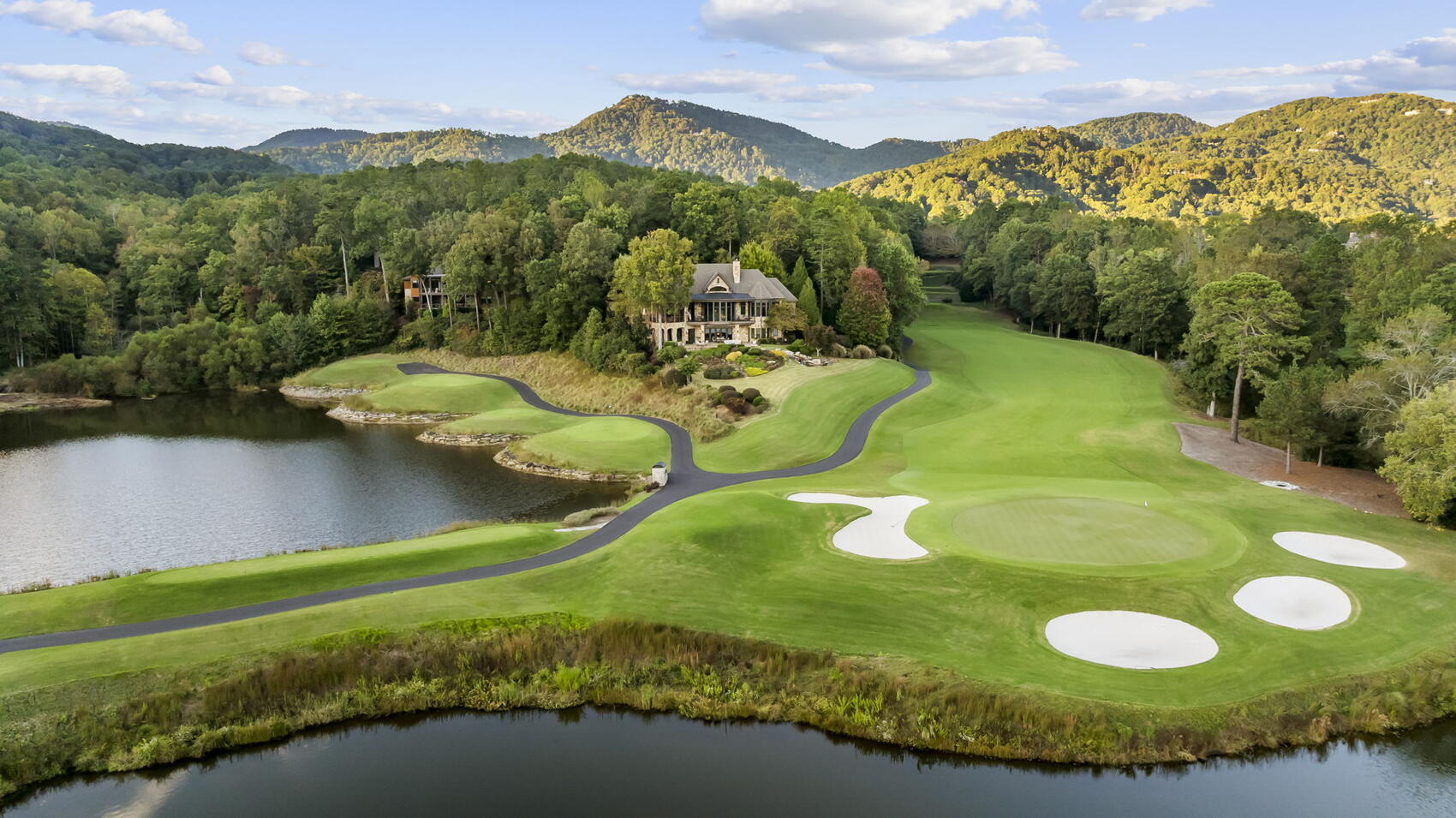 Aerial of a Cliffs Valley green and pond with mountains behind
